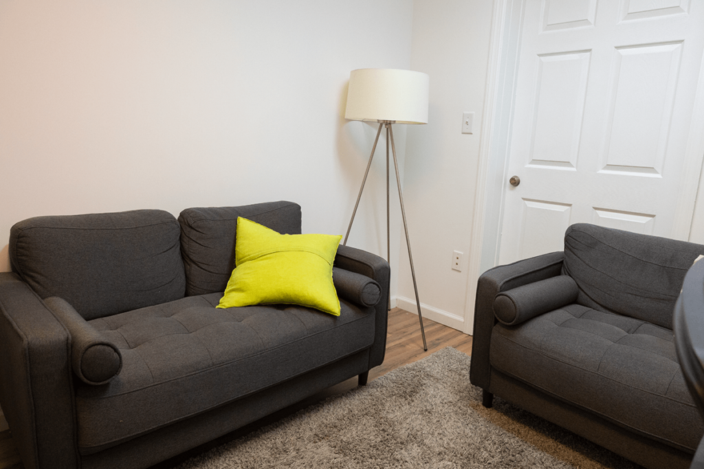 a lamp and two small sofas sit in the office of a therapist or counselor at harmony