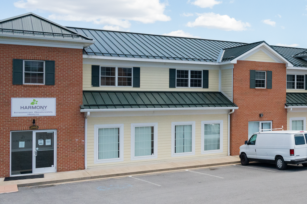 front facade of harmony building and offices with cars parked in the lot