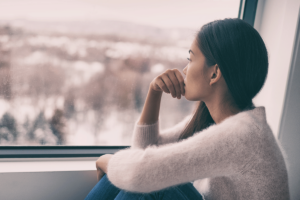 a person looks out a window after learning about blue light and mental health