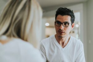 a man stares at and listens to a woman talking about the importance of mental health disorder treatment