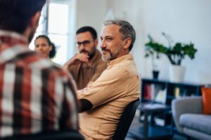 man sits and listens in a group therapy session at his ptsd treatment program