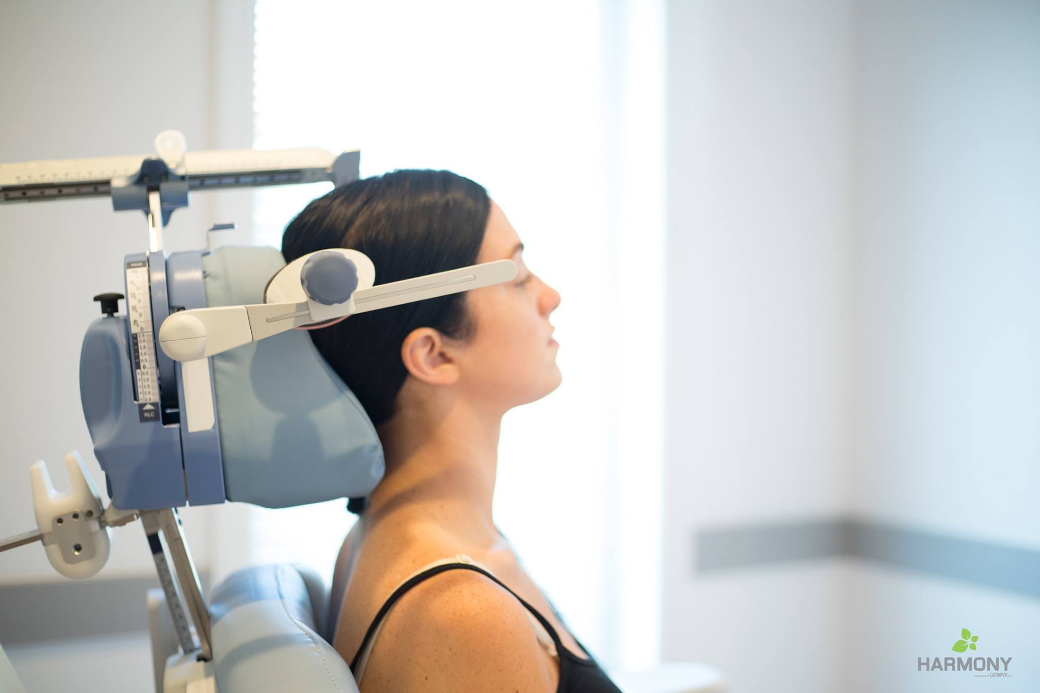 a woman with brown hair reclines in an office chair as she receives tms therapy
