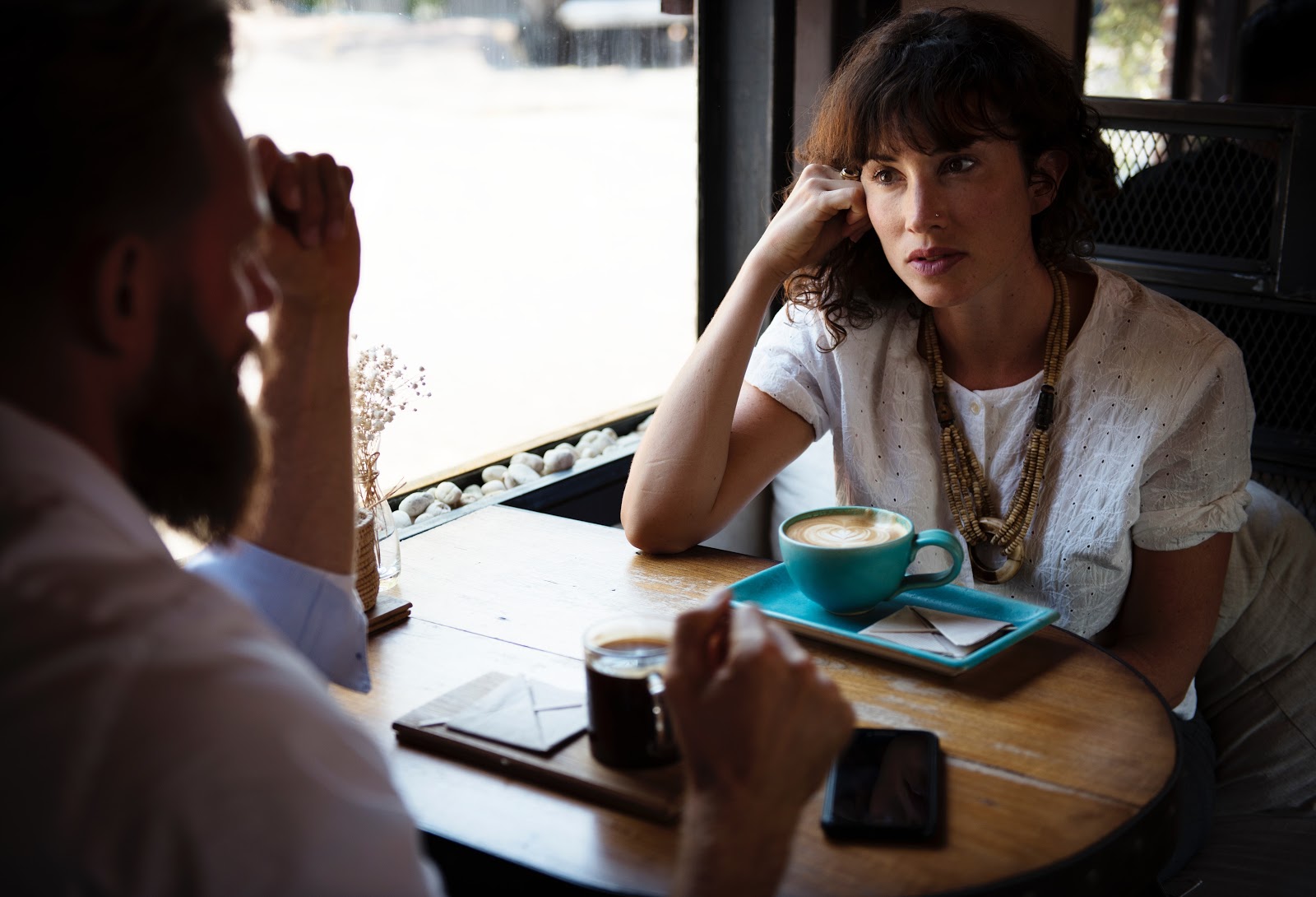 Woman listening to male while drinking coffee