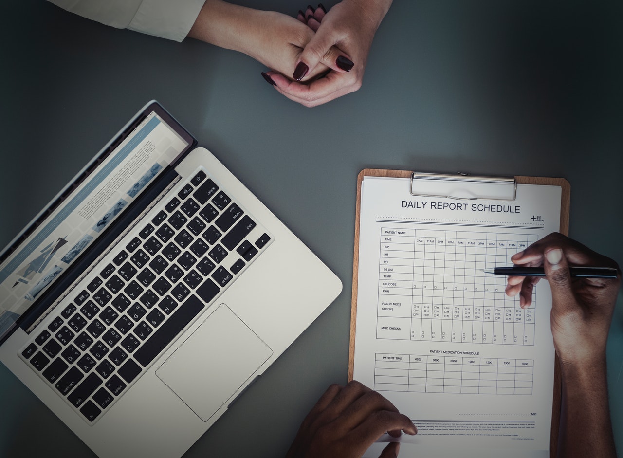 A laptop sits on a table as a mental health professional fills out a neuropsychological evaluation for a patient.