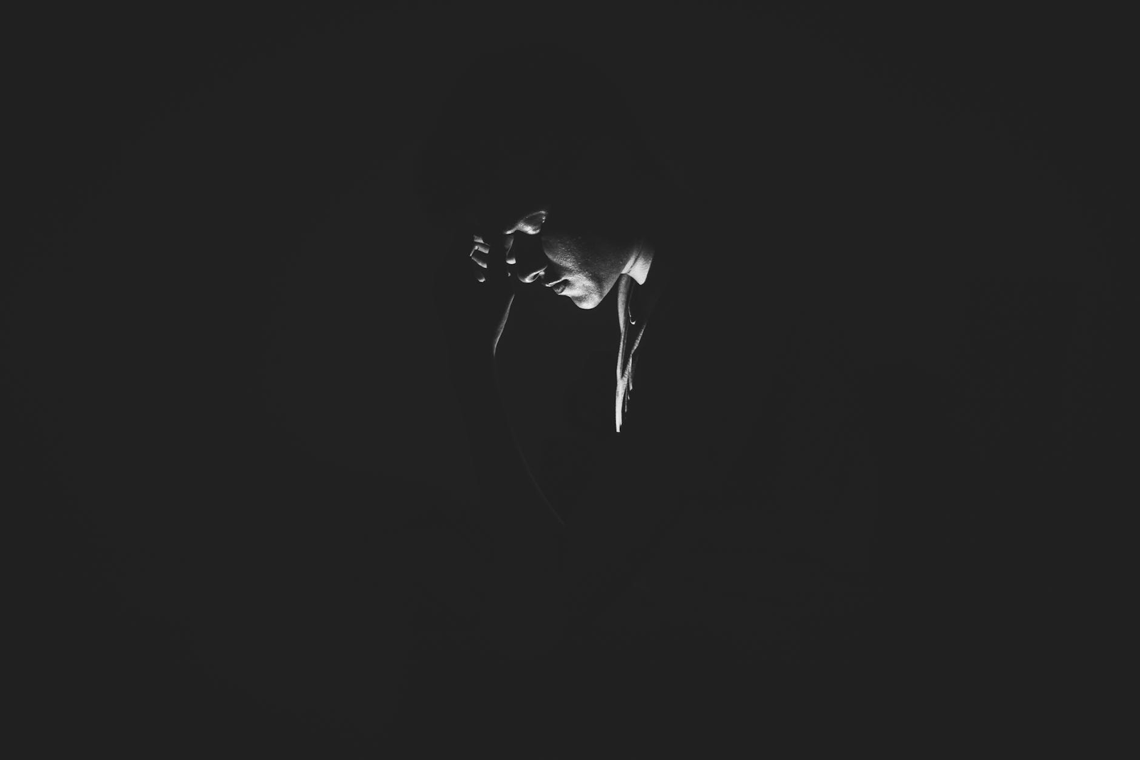 a darkened image. the only thing visible is a face, illuminated by the glow a phone
