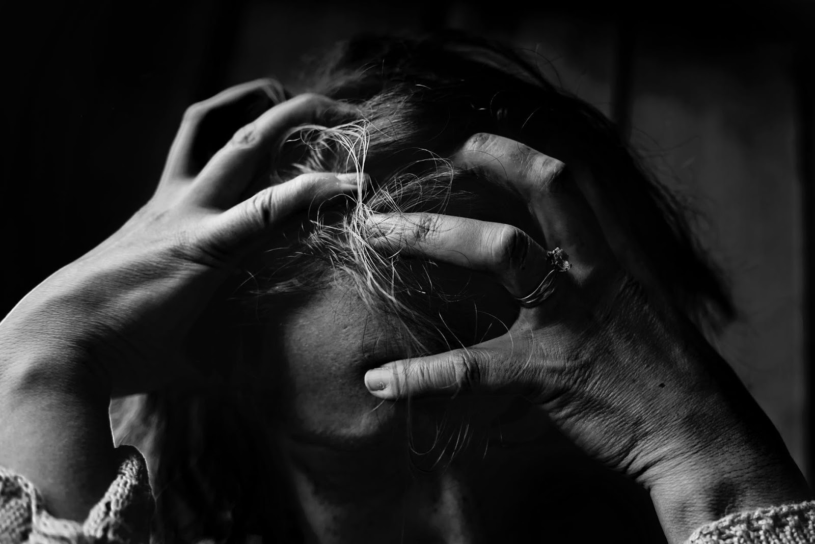A woman is clutching her head out of frustration from her stressful relationship.
