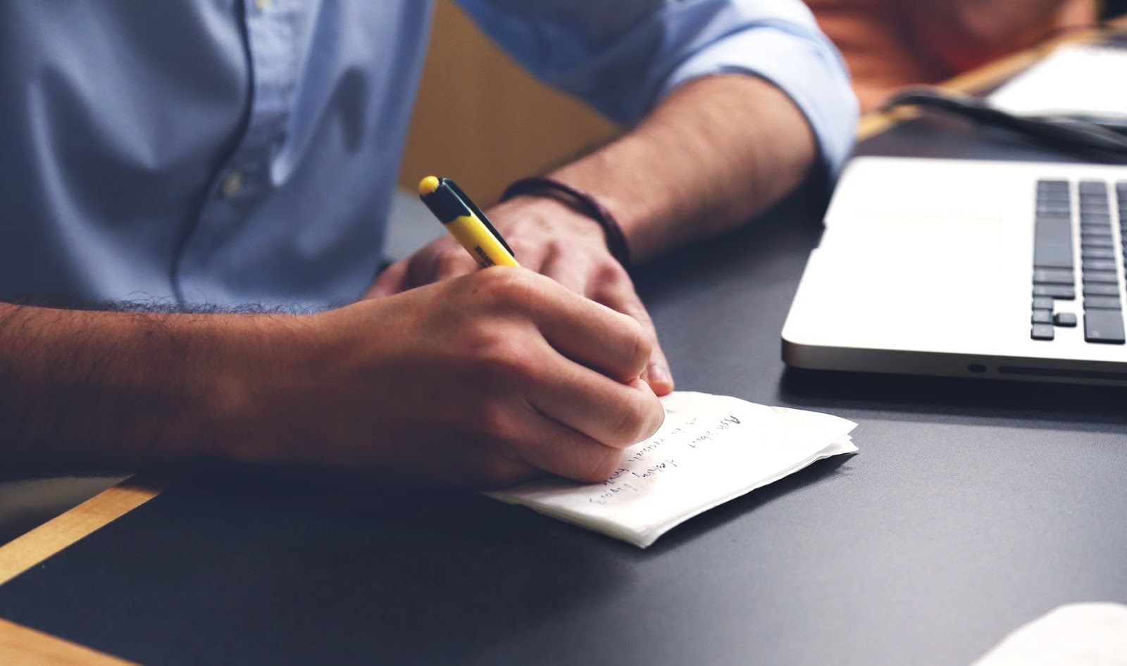 A man sits at his desk with a pen in his hand to write a list.