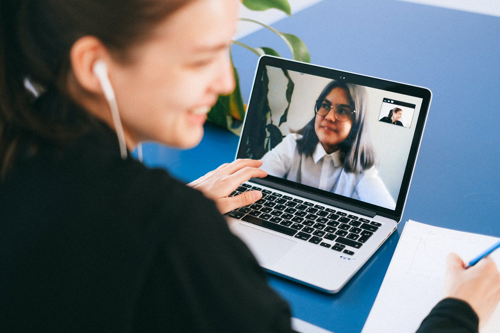 A woman chats and laughs with her friend through a video call on her laptop