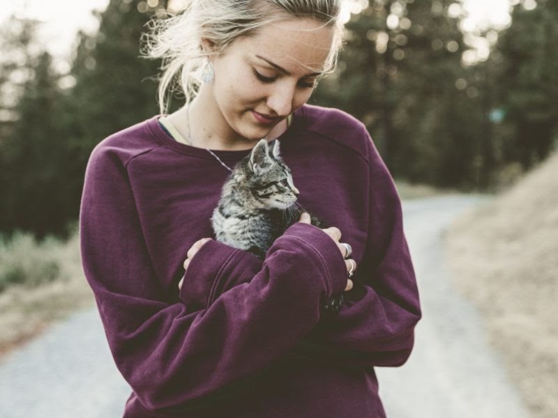 A woman cuddling a kitten. 