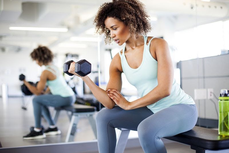 A woman lifts a small weight at the gym. 