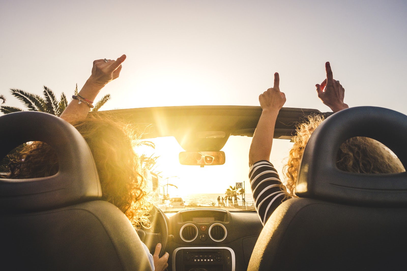 Two friends driving in a convertible as the sun sets.