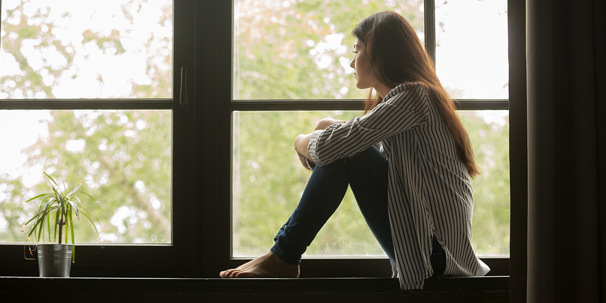 A woman sitting on a ledge by a window.