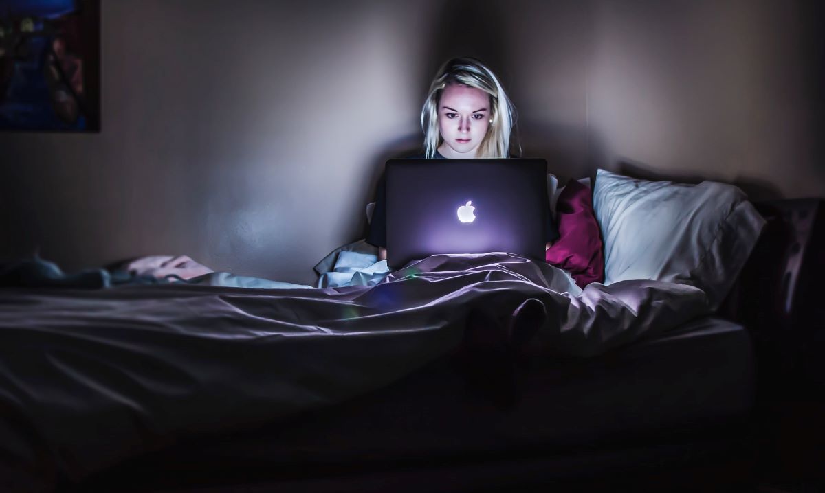 A young woman typing on her computer at night