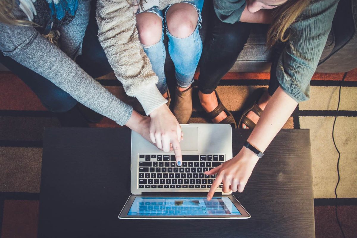 Three Teenagers Look at Social Media on Their Laptop