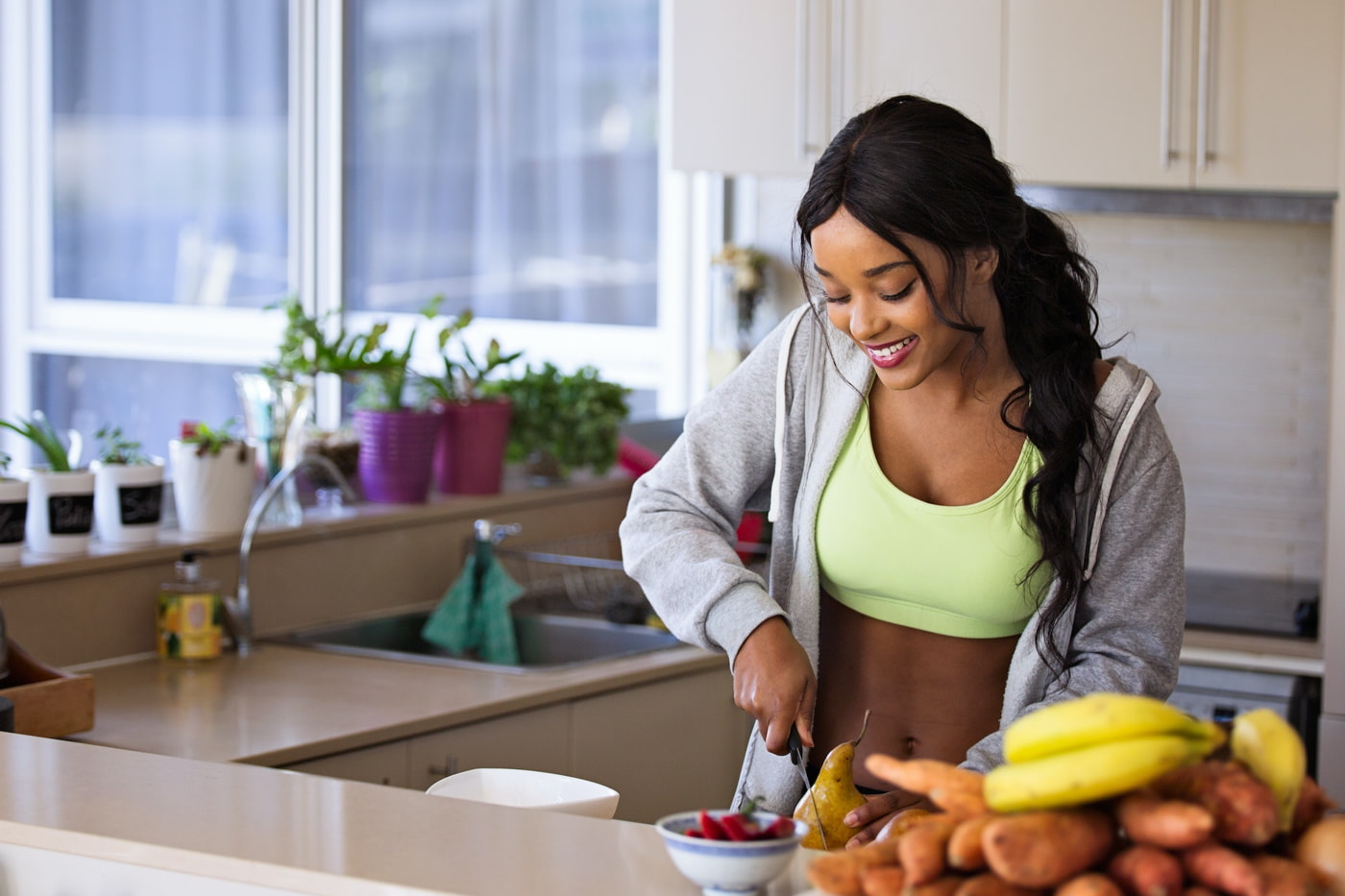  A woman cutting a pear while wearing an outfit perfect for exercising.