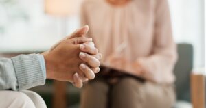 person sitting in therapist's office with hands folded